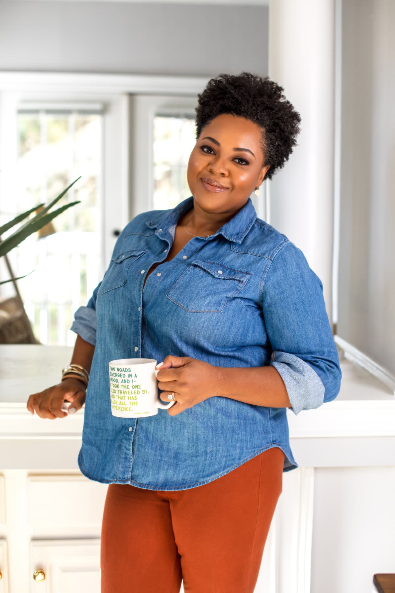 Zakiya Muwwakkil Akerele standing in a bright kitchen holding a mug